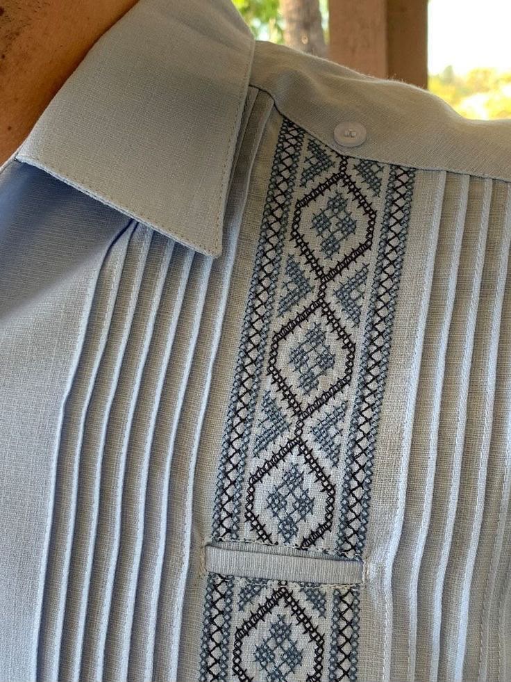 Detalle de bordado y alforzas en camisa de algodón azul claro